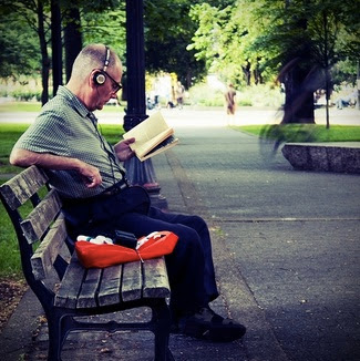 hombre en el parque con un libro y música