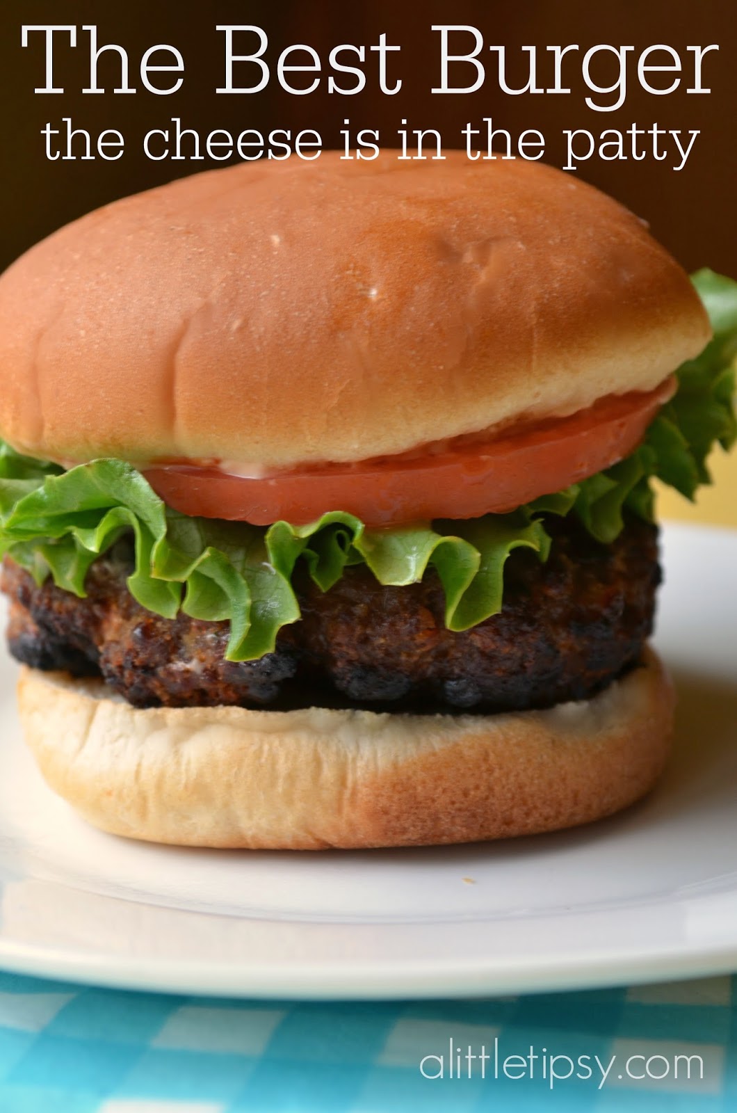 A delicious hamburger with lettuce and tomato on a white plate represents the The Best Burger Recipe