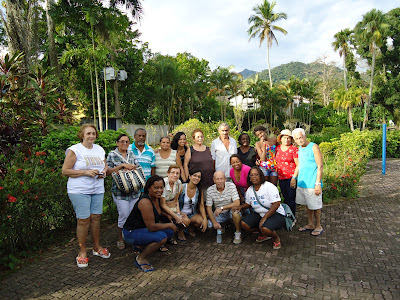 Grupo de Idosos posa ao lado de profissionais de saúde nos jardins do parque aquático. 