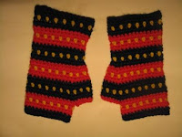A pair of fingerless mitts in Adelaide Crows' colours. They have horizontal stripes, alternating navy and red. Each stripe has a row of yellow dots centred horizontally on the stripe. For example, starting at the cuff the colours are solid navy, yellow dots against the navy, solid navy; solid red, yellow dots against the red, solid red; and so forth ending with a row of solid navy at the fingers.