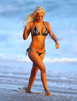 Ashley Kirk walking on the beach in a tiny bikini