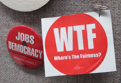 Red round sticker pinned to a bulletin board, reads WTF (Where's the Fairness?)