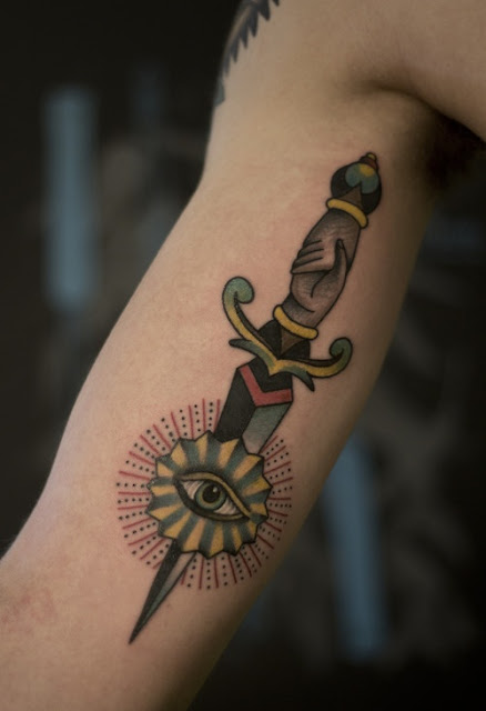 Knife and wounded eye tattoo on arm