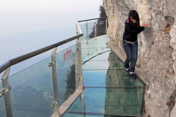 Skywalk On Tianmen Mountain — China Jutting out from a sheer cliff 1,430 meters high, the glass skywalk in Zhangjiajie National Forest Park offers sightseers terrifying thrills and clear view of the mountains below as they tread nervously across the 60 meter long bridge encircling the vertical cliffs of Tianmen Mountain in Hunan province. The 3ft-wide, 2.5in thick glass walkway is so scary that sightseers are requested to wear cloth slip-ons over their shoes when they cross the skywalk, presumably to make the job easier for the cleaners.