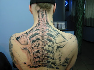 anatomical tattoo: the spine and the ribs are revealed under the ripped skin