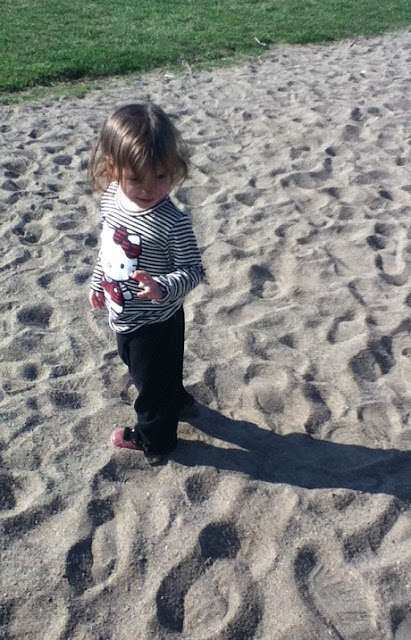 Toddler playing at the park. Toddler in the sand at the park.
