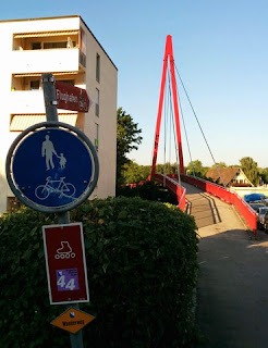 Signs point cyclists, inline skaters, and pedestrians over a bridge toward Zürich International Airport, Switzerland.