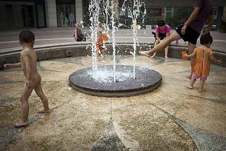 Children and parents play in a fountain