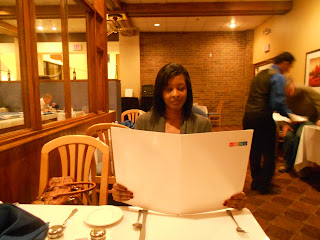 a woman sitting at a table reading a menu