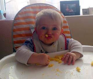 baby pulling face eating crisps