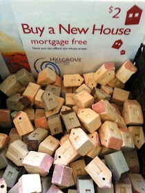 A large number of small clay houses, all jumbled together under a sign which says '$2 Buy a New House mortgage free'
