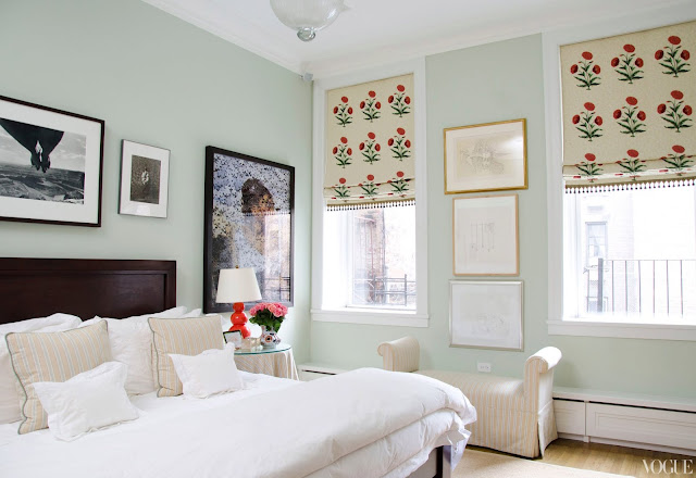 apartment bedroom with mint walls, a wooden headboard, white bedding and floral roman shades.