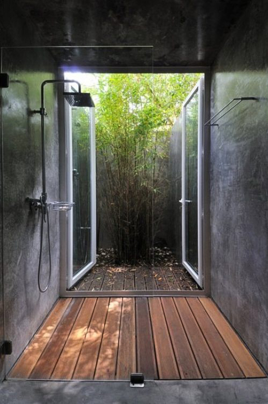 Wooden deck shower with concrete walls and a view to the small yet vibrant patio designed by FVA Architects via Designboom.