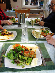 Table with five people eating lunch with glasses of sparkling wine.