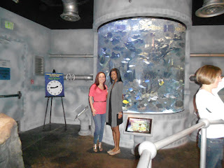 two women standing in front of a large aquarium