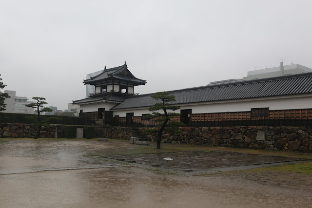 Standing in the middle of the garden at Ninomaru to take a picture of the reconstructed drum tower and Ninomaru Omote Gate at Hiroshima Castle and Tower in Japan Standing in the middle of the garden at Ninomaru to take a picture of the reconstructed drum tower and Ninomaru Omote Gate at Hiroshima Castle and Tower in Japan