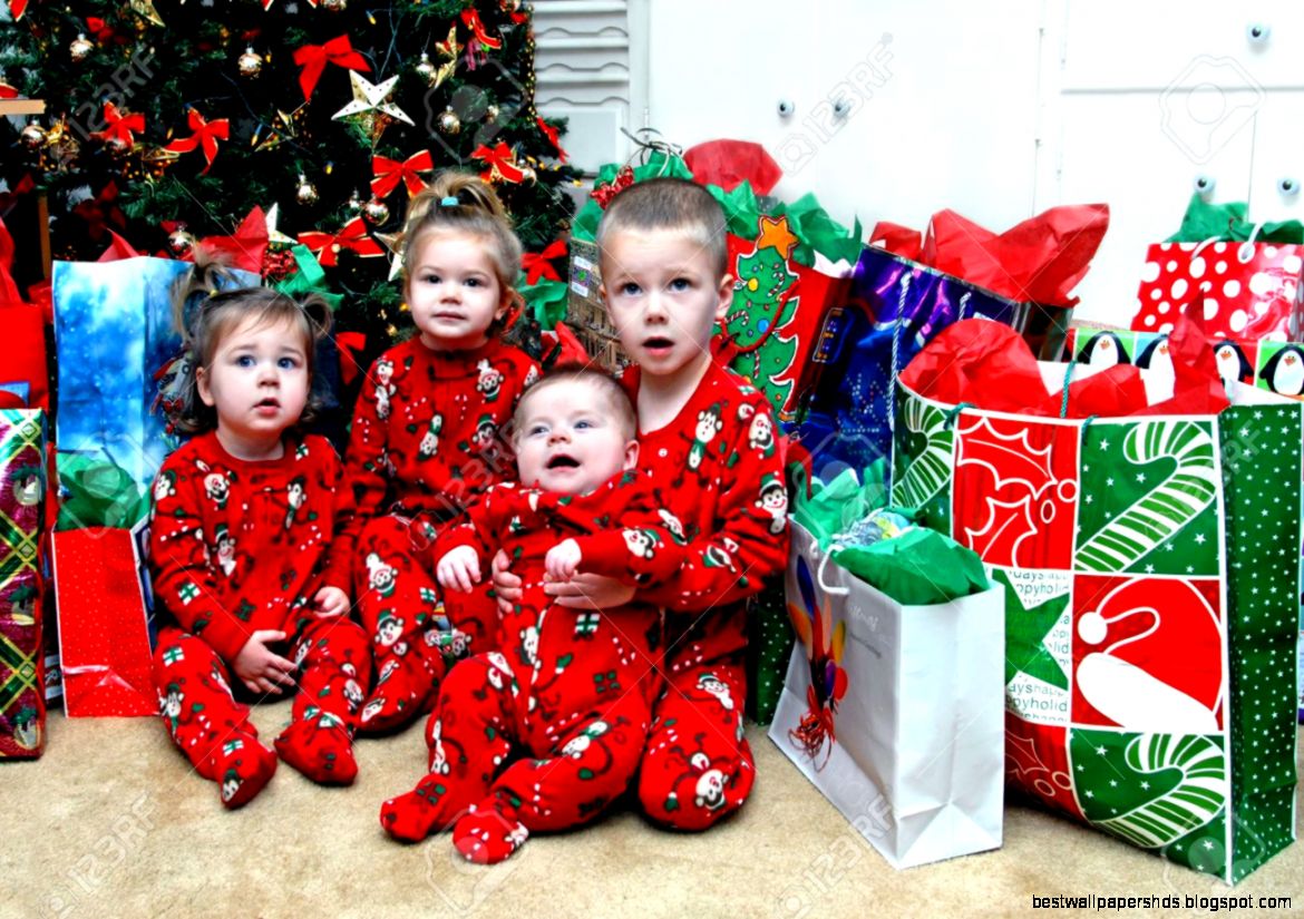 Four Small Children Sit In Front Of The Christmas Tree Surrounded Four Small Children Sit In Front Of The Christmas Tree Surrounded