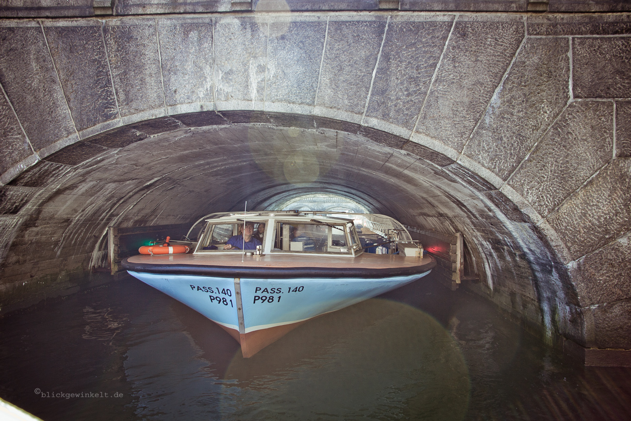 Touristenboot unter enger Brücke