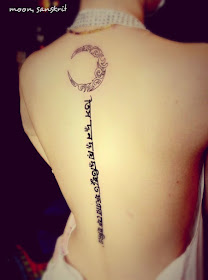 a tattoo combining a crescent moon and sanskrit on the back