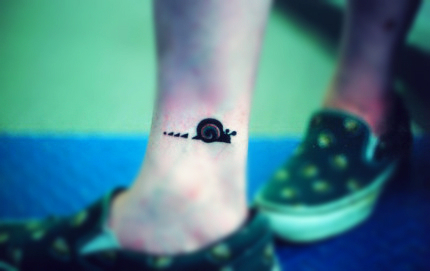 A cute snail tattoo design on the ankle