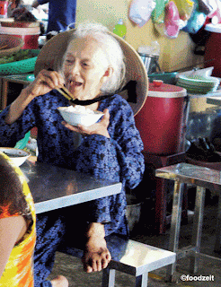 old noodle fan lady eating her noodles ont he wet market