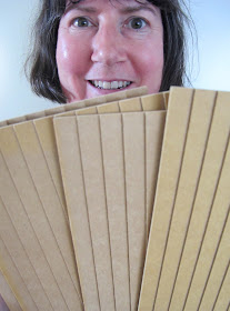 Woman looking happy and holding up four panels of miniature weatherboarding wood.