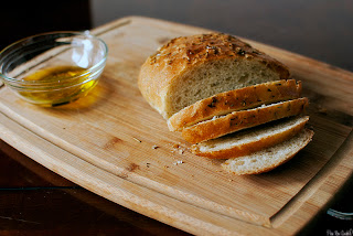 rosemary bread sliced on a cutting board with olive oil in a bowl