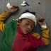 An injured boy sleeps on the ground in Dhading Besi, Nepal