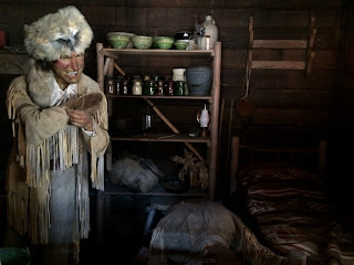 Wax figure male (Davy Crockett) posed in a wooden cabin after shooting an opponent.