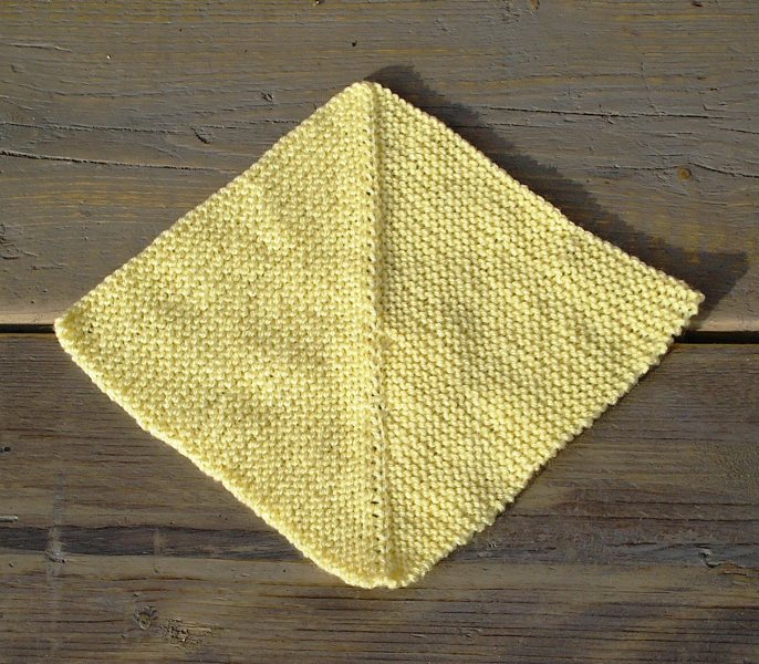 Another yellow knitted square. This time the ridge is more prominent on the top half. The lower half is slightly less prominent on one side, and there are a few mistakes in the ridge itself.