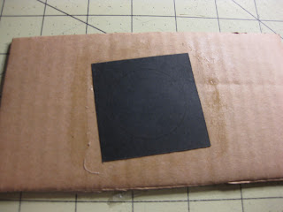 Applying the template to the cardboard base with rubber cement for the LED paper lamp. 