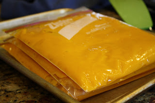 three freezer safe Ziploc bags filled with orange pumpkin puree, laid flat atop a cookie sheet