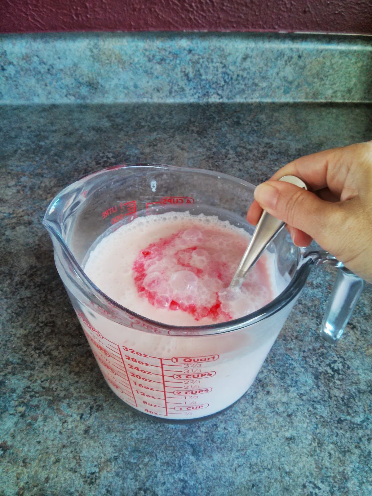 Mixing food coloring into sherbet mix to make it pink