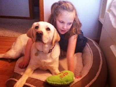 Hallie lies in Widget's bed with her arm around the adorable yellow Lab (a green plush toy that says "FOREVER" is next to them). Hallie lies in Widget's bed with her arm around the adorable yellow Lab (a green plush toy that says "FOREVER" is next to them).