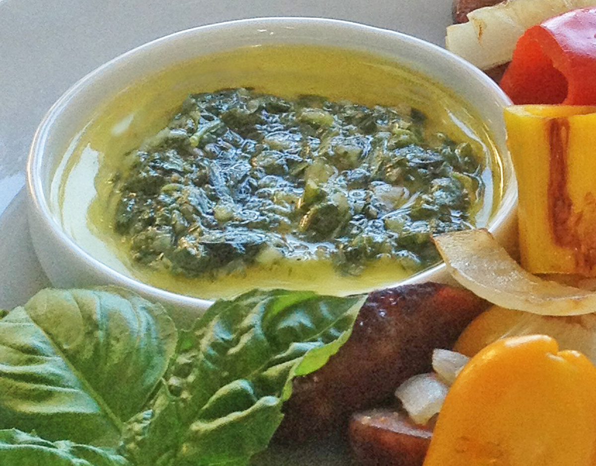 Close up image of basil dipping sauce surrounded by grilled vegetables 