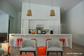 Modern Ikea kitchen in all white modern house accented with orange stools and textured pendants