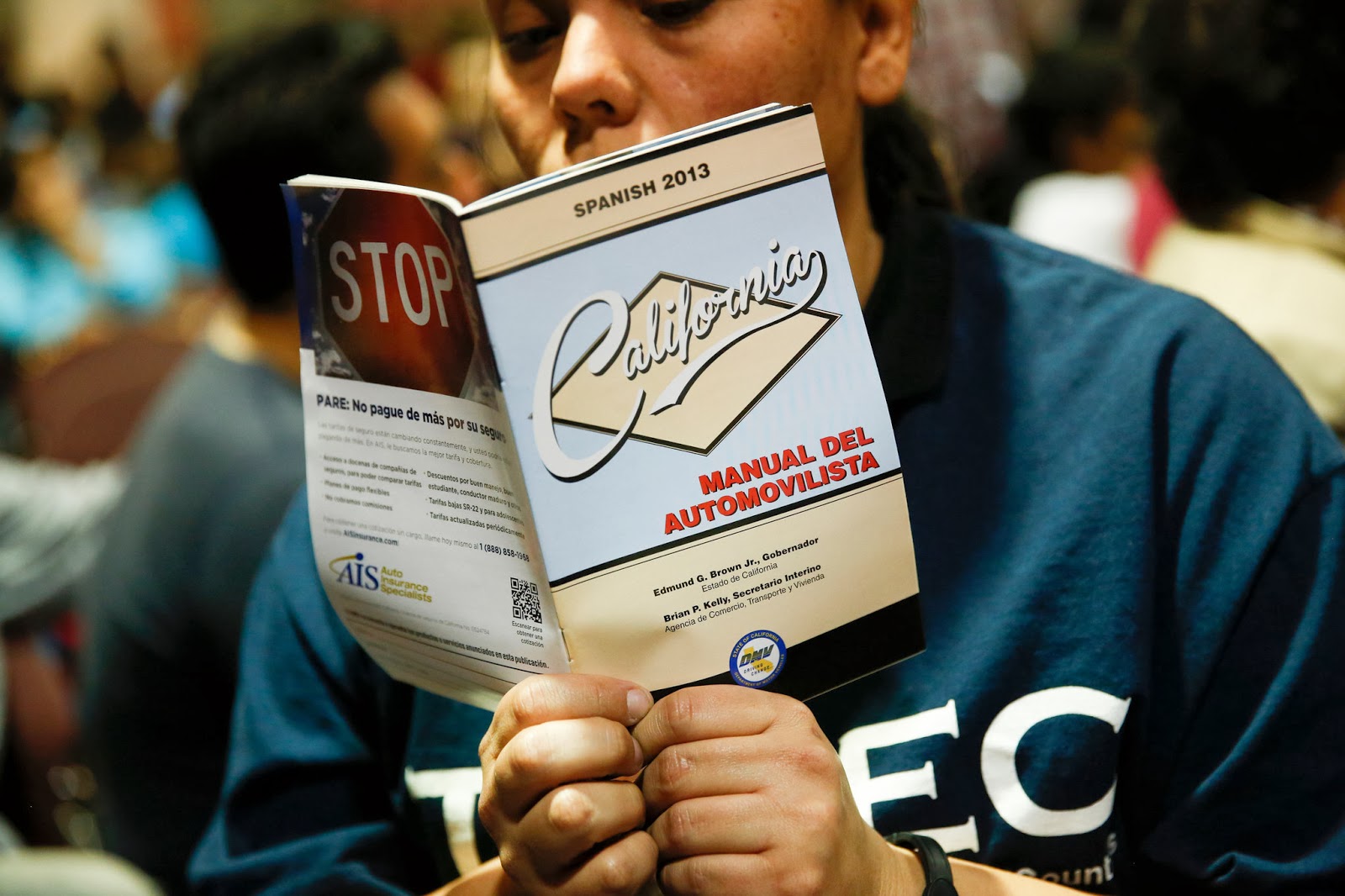 A woman read a Spanish driving handbook while attending the meeting in Bell, CA