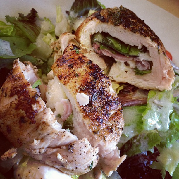 Spinach Ham and Goat Cheese Chicken Roll Over a Bed of Greens