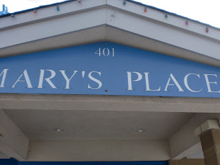 Light blue sign with carved white letters reading MARY'S PLACE