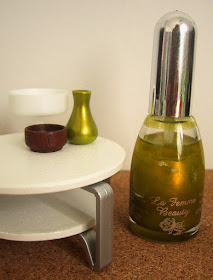 Modern dolls' house miniature coffee table displaying a green vase and two bowls. On the floor next to it is a bottle of nail varnish.
