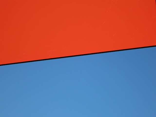 The red of the back of a No-Entry sign against the blue of the sky