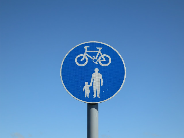 Blue sign to say walkers and bikes allowed. Against blue sky.
