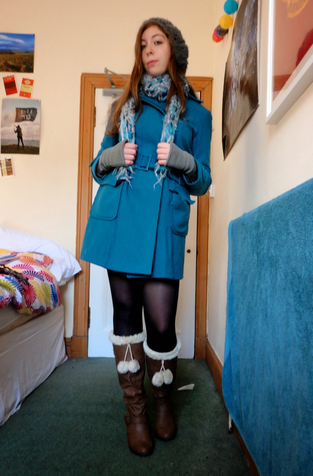 outdoor winter outfit of turquoise blue coat, brown leather boots, grey hat and gloves and blue scarf