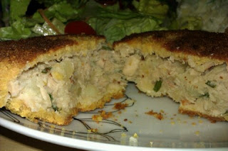 A salmon fish cake cut in half so the insides can be seen served with a fresh green salad