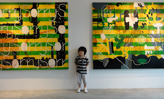 Beng Calma son Leon sandwiched between paintings