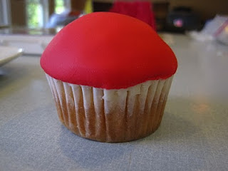 cupcake in white wrapper with red fondant on top