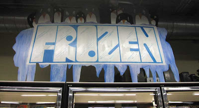 Frozen food sign, hand painted with blue icy letters and shivering penguins above