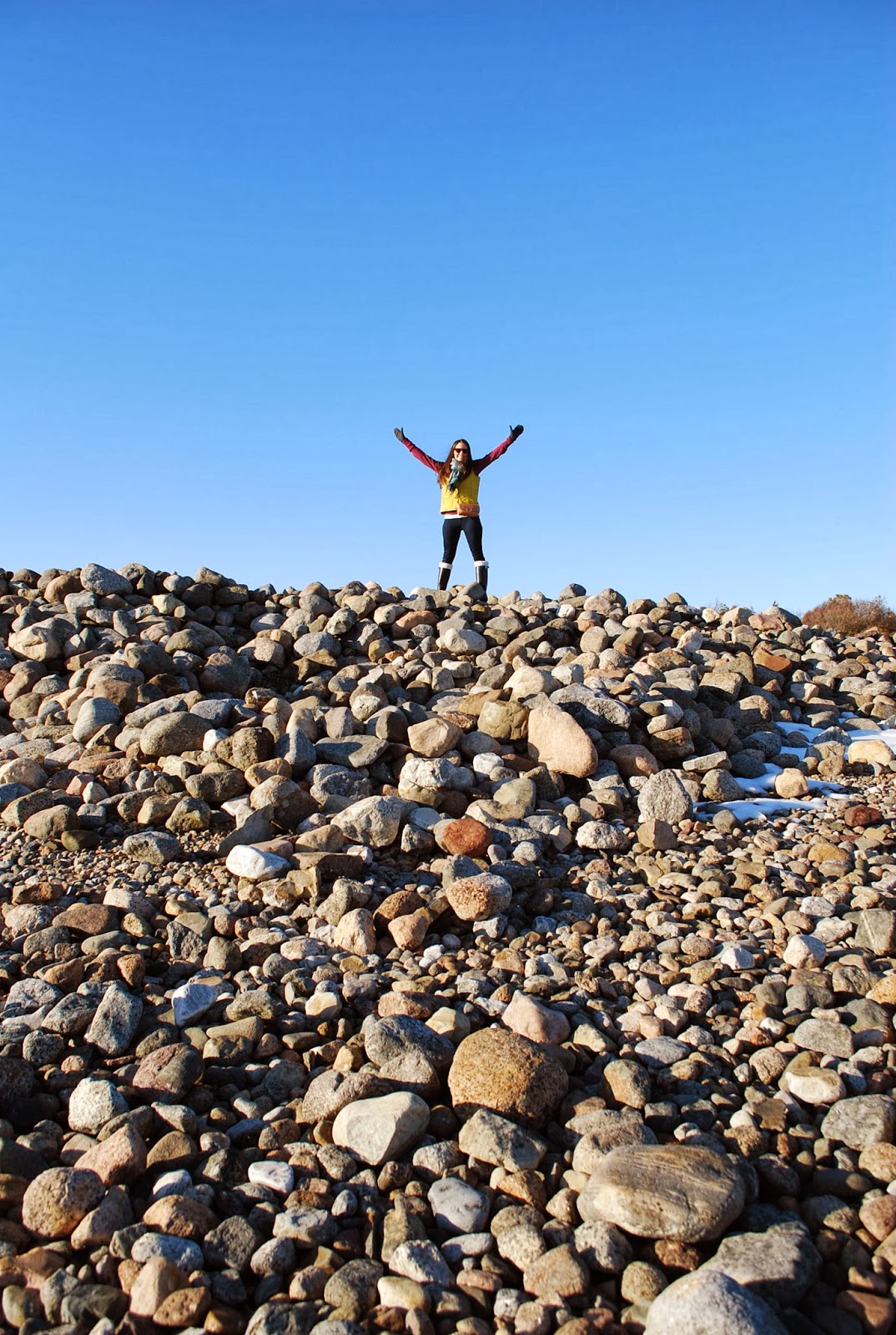Woman standing on top of rock pile in Norway on the shore