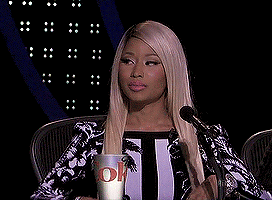 Animated gif of Nicki Minaj raising her eyebrows and looking at someone off screen through the corners of her eyes before turning away.