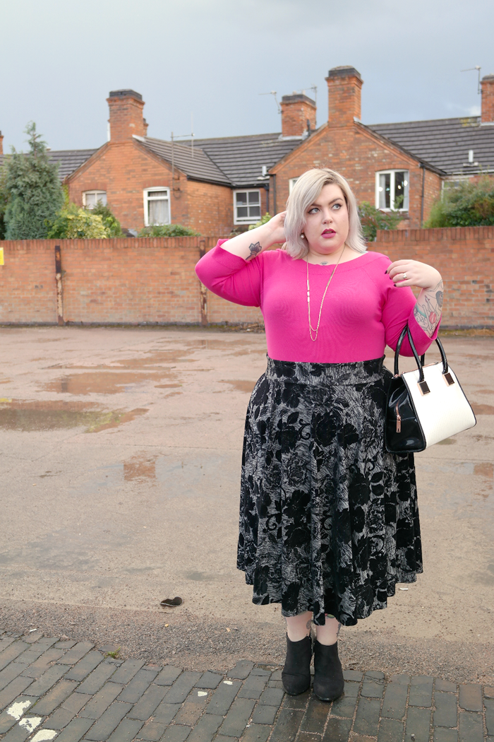 A picture of British Plus Size Fashion Blogger Nancy Whittington-Coates in pink sweater and grey floral skirt www.sugar-darling.com